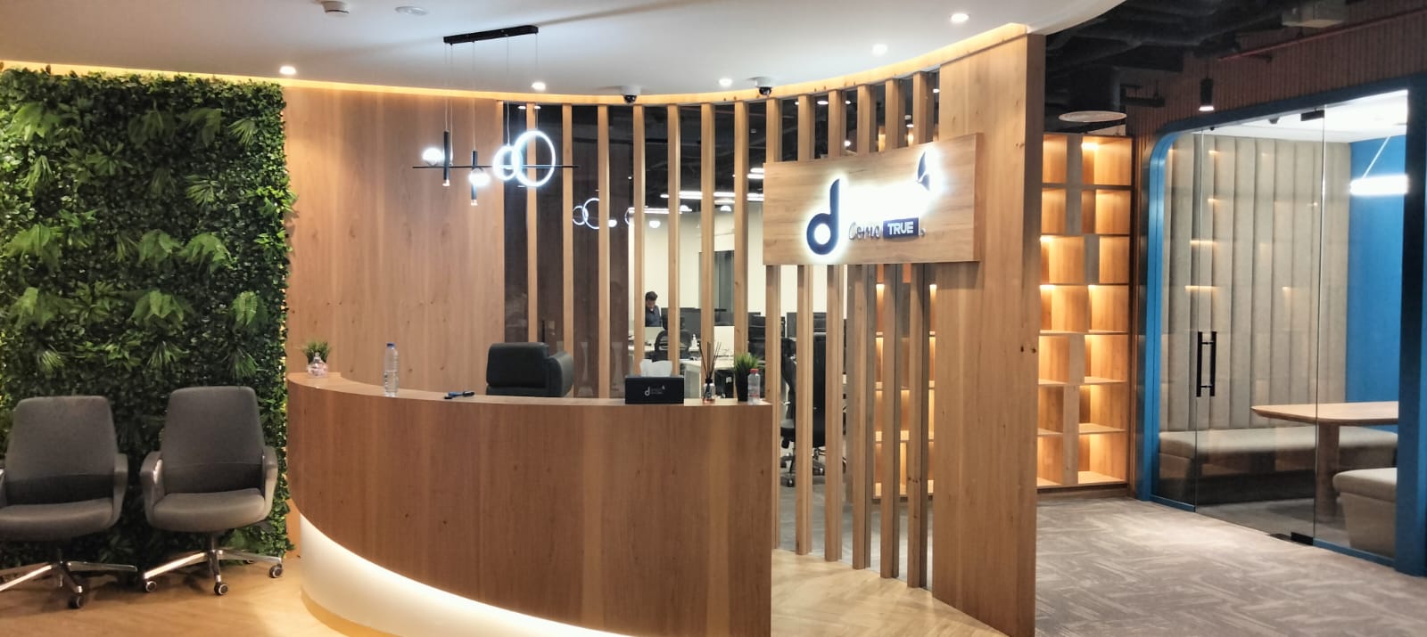 Commercial office reception with curved wood desk and living green wall by Mistry Interiors